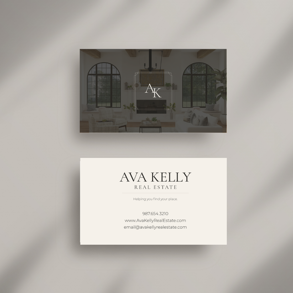 Two real estate business cards displayed on a light gray background with soft diagonal shadows. The top card is dark charcoal with a faint interior room photo and a central monogram logo reading AK.